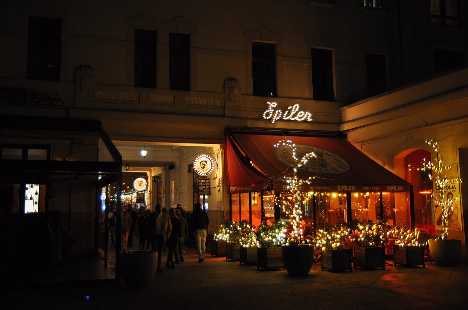 De Gozsdu-passage in de Joodse wijk bij avond, met een restaurant met lichtjes in de bomen en uitgaanspubliek