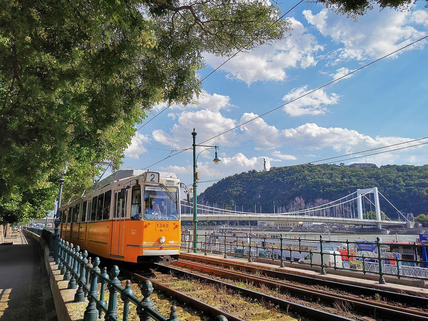 Een gele tram van lijn 2 langs de Donaukade, met de Elisabethbrug en de Gellértheuvel op de achtergrond